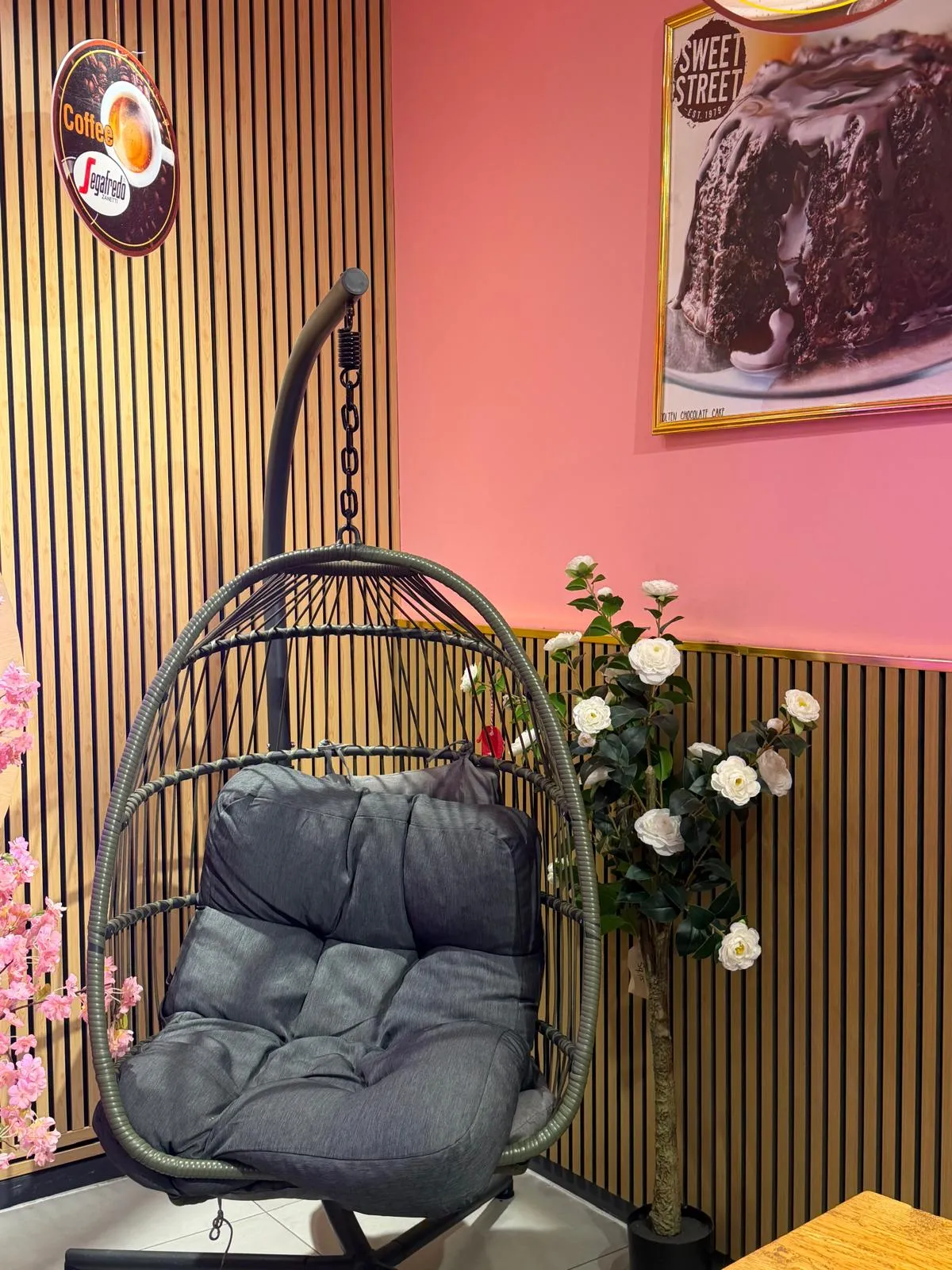 A hanging egg chair beside the pink wall at the back of the shop